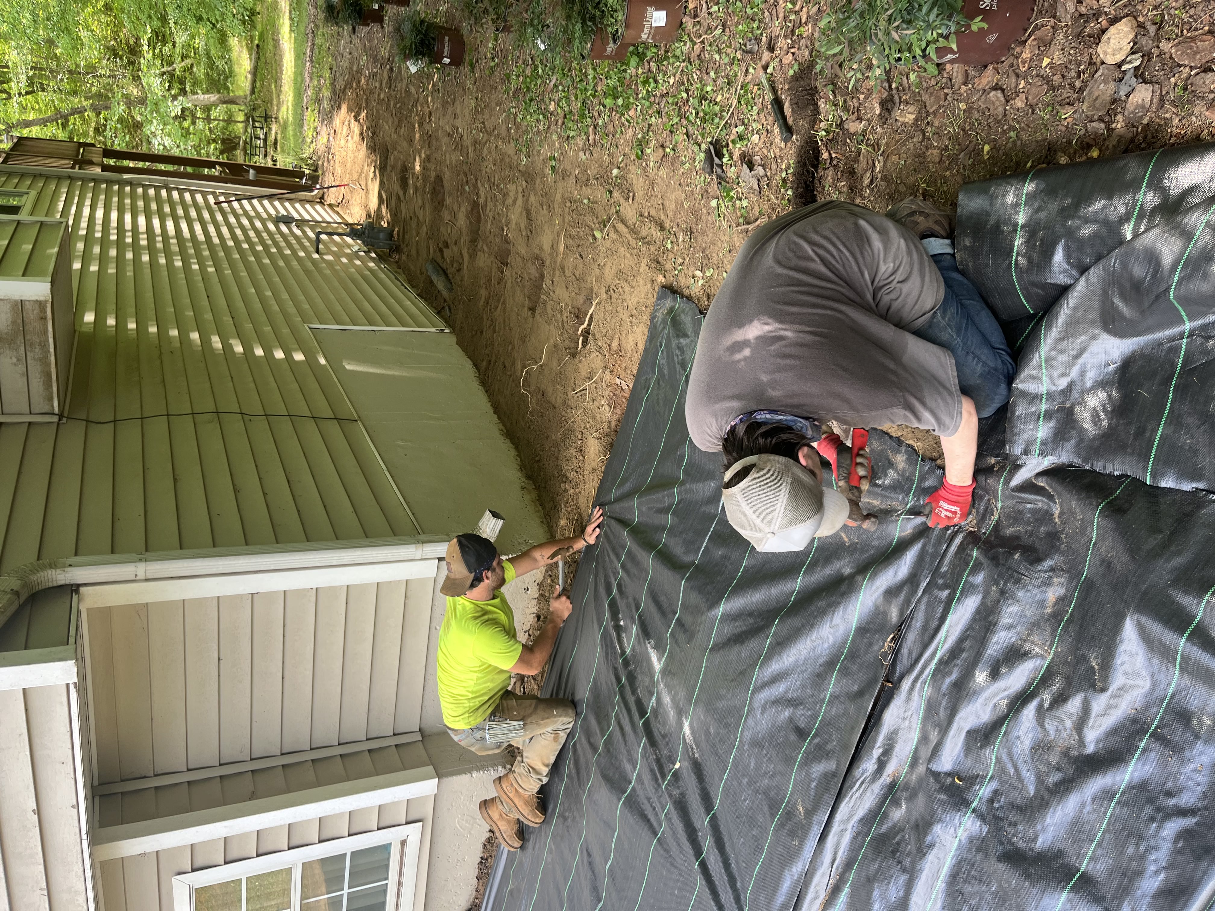 SD Lawn Maintenance crew installing landscape fabric and a retaining wall on a Cherokee County job site